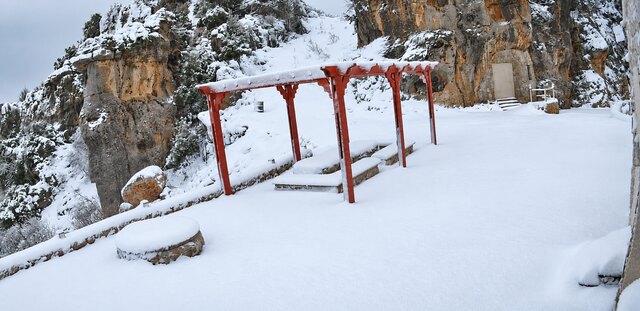 Deep snow over the terrace, the red pergola and the stone benches buried after a January fall.