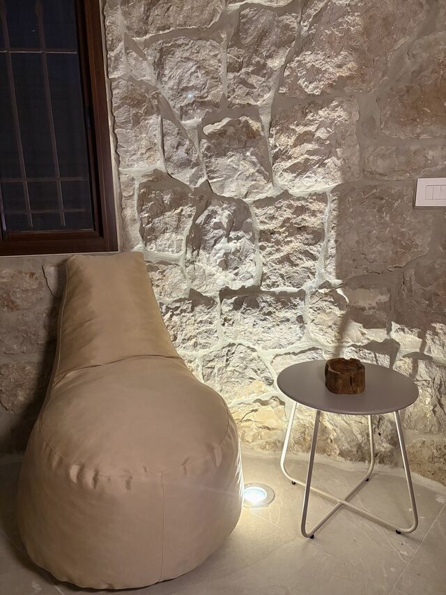A reading corner in La Grotta: a bean bag chair against the rock wall next to the window and a small side table.
