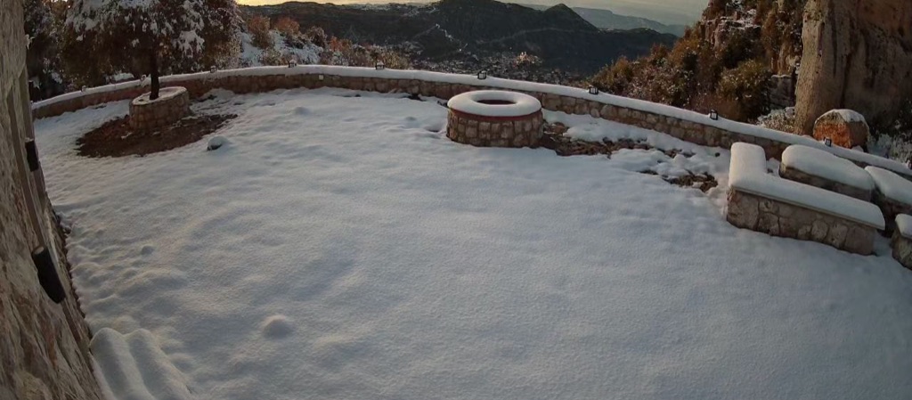 Snow lying across the Cap de Douma terrace and stone wall, with the valley beyond.